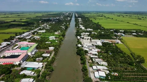 Drone flying forward over a long rural canal and riverside village Vídeos de archivo 335859011
