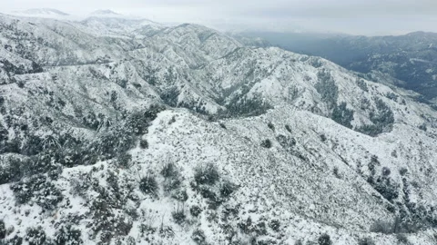 Drone flying forward through the snowfall or winter storm above snowy mountain Видео 145363601