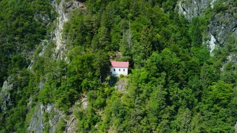 Drone flying forward toward white cottage with red roof on mountain slope Stock Footage 314192330