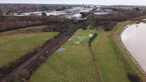 Drone flying forward as train passes under road bridge toward trading estate Stock Footage 327140305