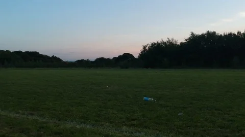 Drone flying on grass leading to a plastic bottle Stock Footage 92557263