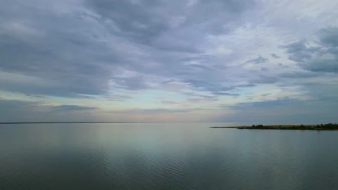 Drone flying high above a large lake with evening-colored clouds.  Stock Footage 155128867