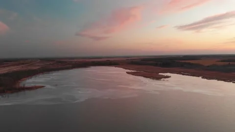 Drone flying high above a partially frozen lake at sunset Stock Footage 143194936