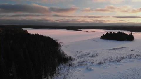 Drone flying high above the treetops at sunset looking down on a frozen lake  Stock Footage 135273684
