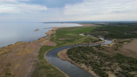 Drone flying high above a winding river and large lake that are reflecting cloud Stock Footage 155128976