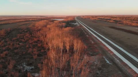 Drone flying high above a winter forest, farm fields and two-lane highway  Stock Footage 144386419