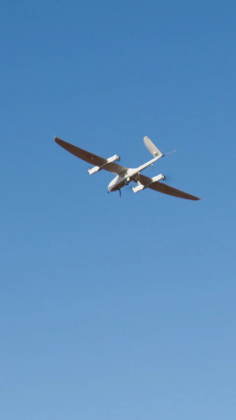 Drone flying high in a clear blue sky, showcasing its sleek design and Stock Footage 314307824
