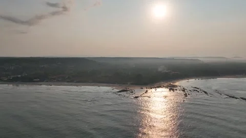 Drone flying high over the ocean looking towards a sunlit tropical beach an.. 库存影片 339548707