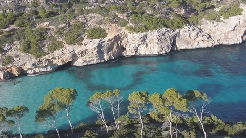 Drone flying left across trees in front of virgin beach Calo des Moro  Stock Footage 100262577