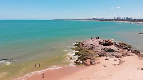 Drone flying left to right showing some people fishing on the rock in the 스톡 동영상 132332873