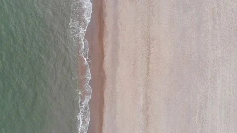 Drone flying looking at the water hitting the sand on a beach in united kingdom Stock Footage 141463214