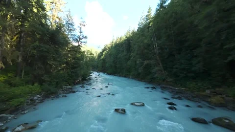 Drone flying low and fast upstream over a milky turquoise mountain river bend Stock Footage 342764988