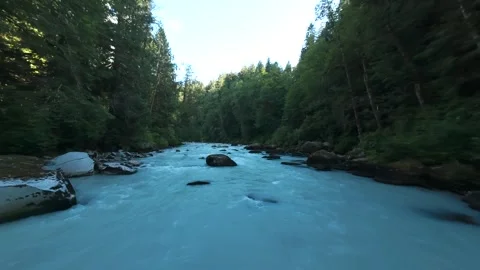 Drone flying low and fast upstream over a milky turquoise mountain river bend Stock Footage 342765040