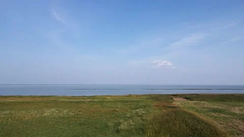 Drone flying low and forward over marshy grass and then out over a large lake  Stock Footage 257724242