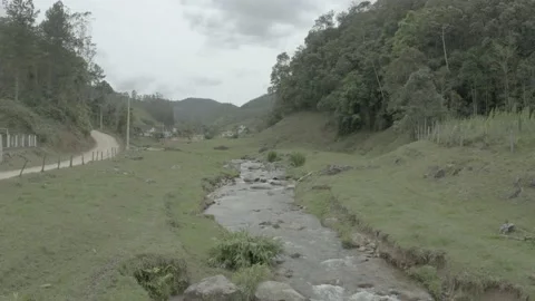 Drone flying low next to road over river with waterfall in background Stock Footage 234341218