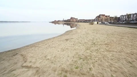 Drone flying low over a beach near a town with buildings Stock Footage 75352045