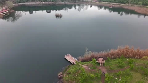 Drone Flying Low Over Calm Lake From Pier Toward Road Traffic Ahead Video stock 335524089