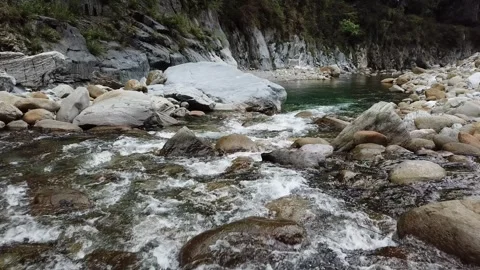 Drone flying low over clear river with rock formations (Taiwan) Stockbeeldmateriaal 329052271