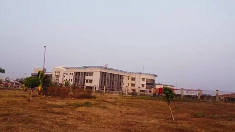 Drone flying low over dry grass towards the NILDS office building in Abuja Stock Footage 328858390