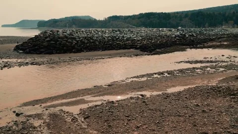 Drone Flying Low Over Harbour At Low Tide With A Rise Revealing Beautiful Ocean Video stock 254998329