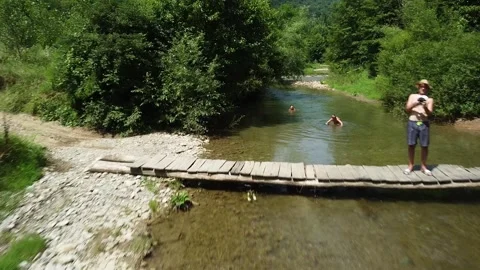 Drone Flying Low Over Mountain River Towards Pilot and Family Swimming Stock Footage 330531103