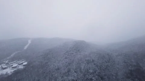 Drone flying low over snowy river valley in snowstorm Stock Footage 321251756