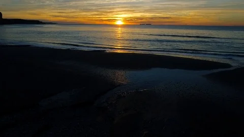 Drone flying lower over coast looking the sun reflection in a pond and sea 動画素材 90971434