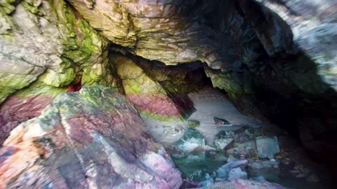 Drone flying out of a colourful cave situated in a cliff Stock Footage 272604904