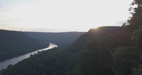 Drone Flying Out of Dense Forest Revealing River, Mountains, and Sunset Stock Footage 313989129