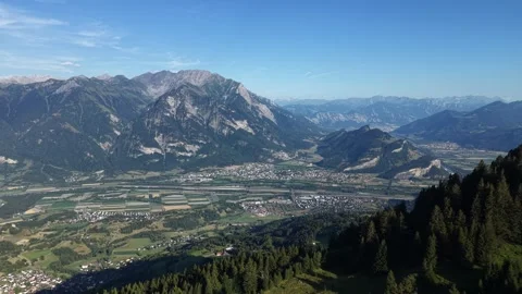 Drone flying over alpine mountain revealing Rhine Valley and Swiss Alps Stock Footage 339645445