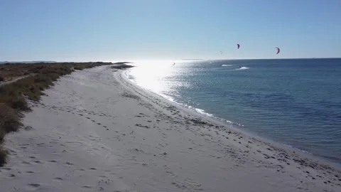 Drone flying over a beach with kite surfers in the ocean 스톡 동영상 330977770