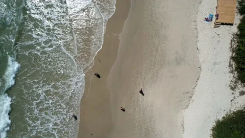 Drone flying over a beach with people running Stock Footage 229853710