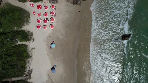 Drone flying over a beautiful beach with calm waves and umbrellas on the sand Stock Footage 229853432