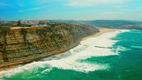 Drone is flying over blue ocean towards sandy beach next to rocky coastline.. Stock Footage 239579909