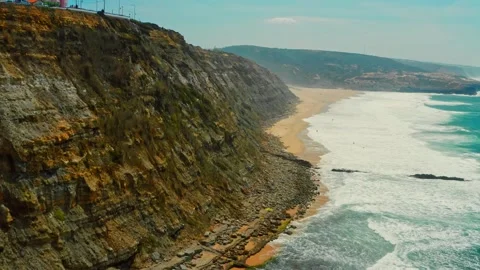 Drone is flying over blue ocean towards sandy beach next to rocky coastline.. Stock Footage 266944629