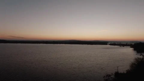 Drone Flying Over Calm Lake at Dusk, Orange Horizon and Twilight Sky, Wide Shot Vídeo Stock 341295080