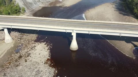 Drone flying over concrete bridge over river with rolling hills in background Stock Footage 253522444