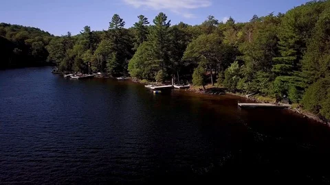 Drone Flying over Cottage Docks on Lake with Canada and Germany Flags Stock Footage 115759486