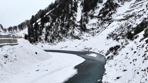 Drone flying over crystal-clear blue water unveiling a winter valley blanket of Stock Footage 310223503