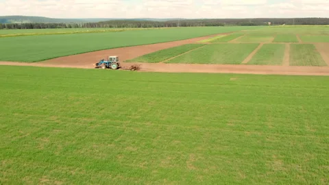 Drone flying over field and blue cultivation tractor driving on a ground road. Stock Footage 142932222