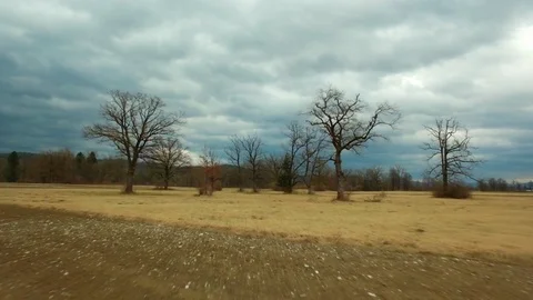 Drone flying over a field surrounded by trees showing the stormy clouds Video stock 89616875