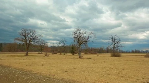 Drone flying over a field surrounded by trees showing the stormy clouds Video stock 89617166