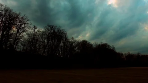 Drone flying over a field surrounded by trees showing the stormy clouds Stock Footage 89619539