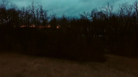 Drone flying over a field surrounded by trees showing the stormy clouds Video stock 89619923