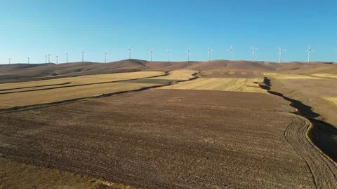 Drone flying over fields and wind turbines in the distance 動画素材 249992608