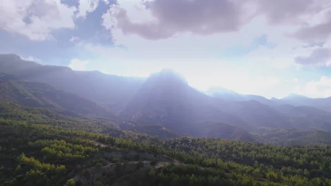 Drone Flying Over a Forest with Stunning Mountain Backdrop and Sun Rays Shining Vídeo Stock 293201853
