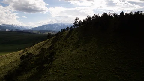Drone flying over forested hill and view of high mountains on horizon Stock Footage 124225727