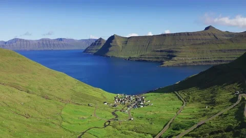 Drone flying over grass covered cliff and blue sea. Village at the basement of 動画素材 169693707