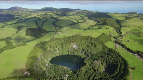 Drone  flying over green round lake surrounded by forest Lagoa do Congro Azores Stock Footage 233912783