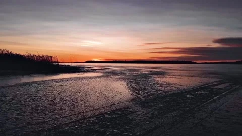 Drone flying over ice during sunset with snowmobile tracks Stock Footage 139039895